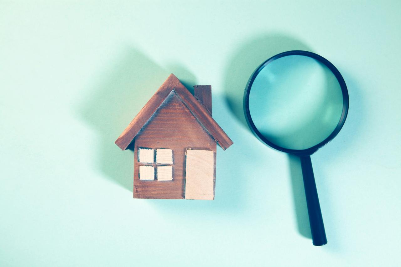 Magnifying glass over a wooden house model.