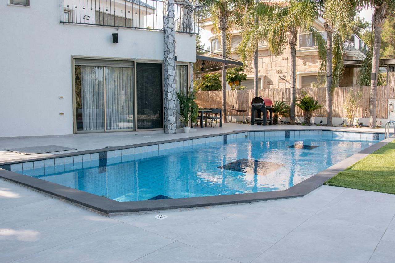 A modern house with a swimming pool and palm trees.