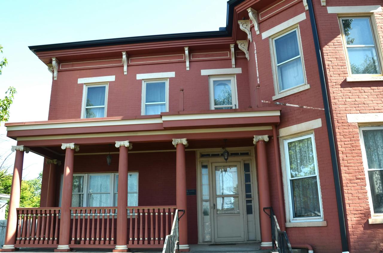 A red victorian house with a porch.