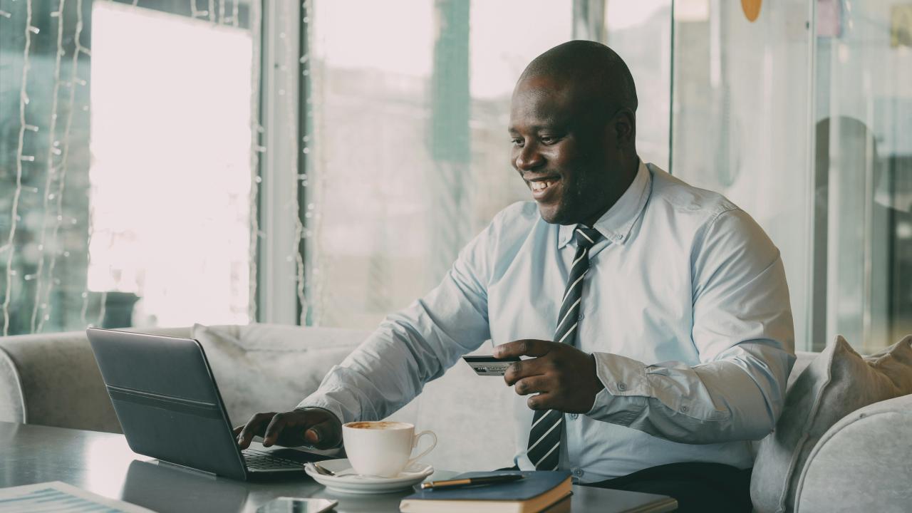 Man with credit card using laptop with coffee.