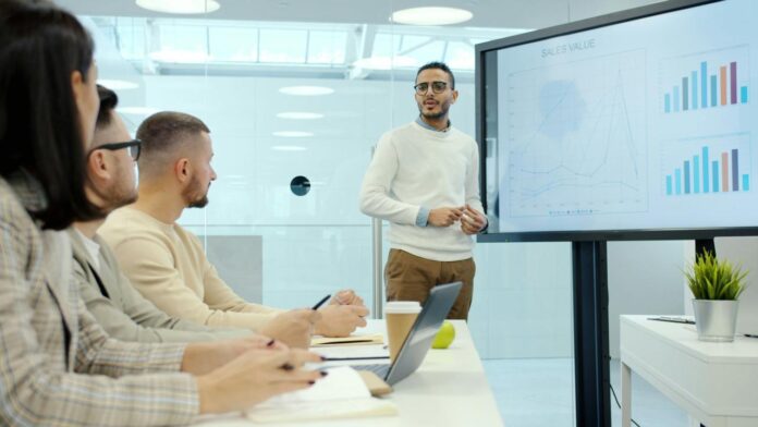 Man presenting charts to colleagues in a meeting.