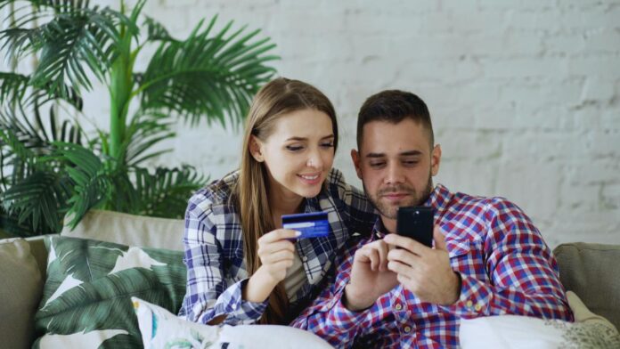 Couple happily shopping online with credit card and phone.